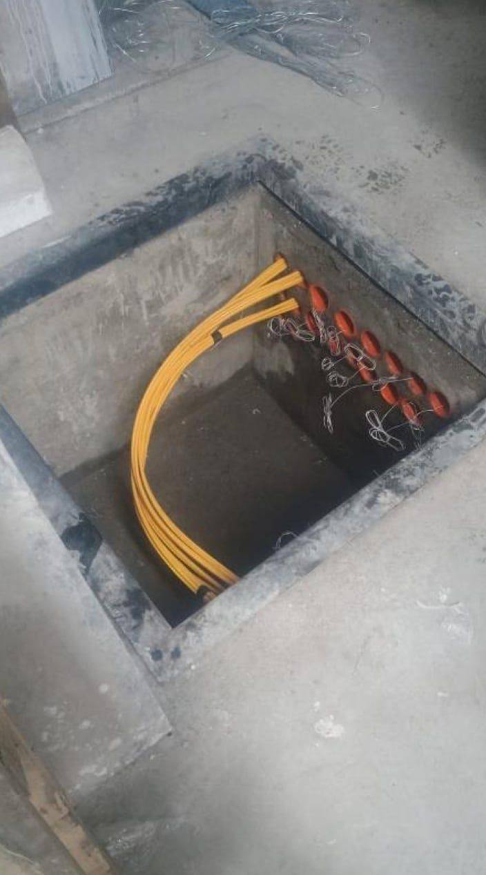Cámara de acceso de telecomunicaciones vista desde arriba, con los ductos de llegada y el cableado de fibra óptica
