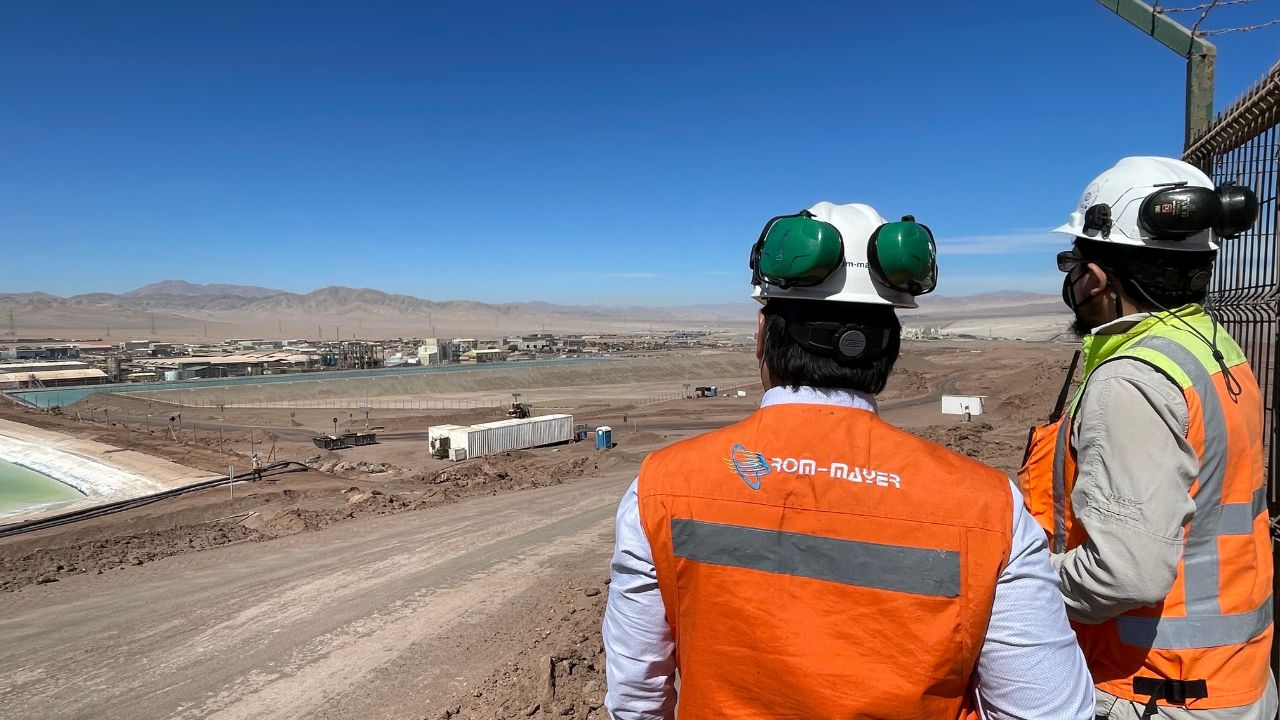 Profesionales de Rom Mayer con casco y chaleco corporativo observan una faena industrial desde un mirador