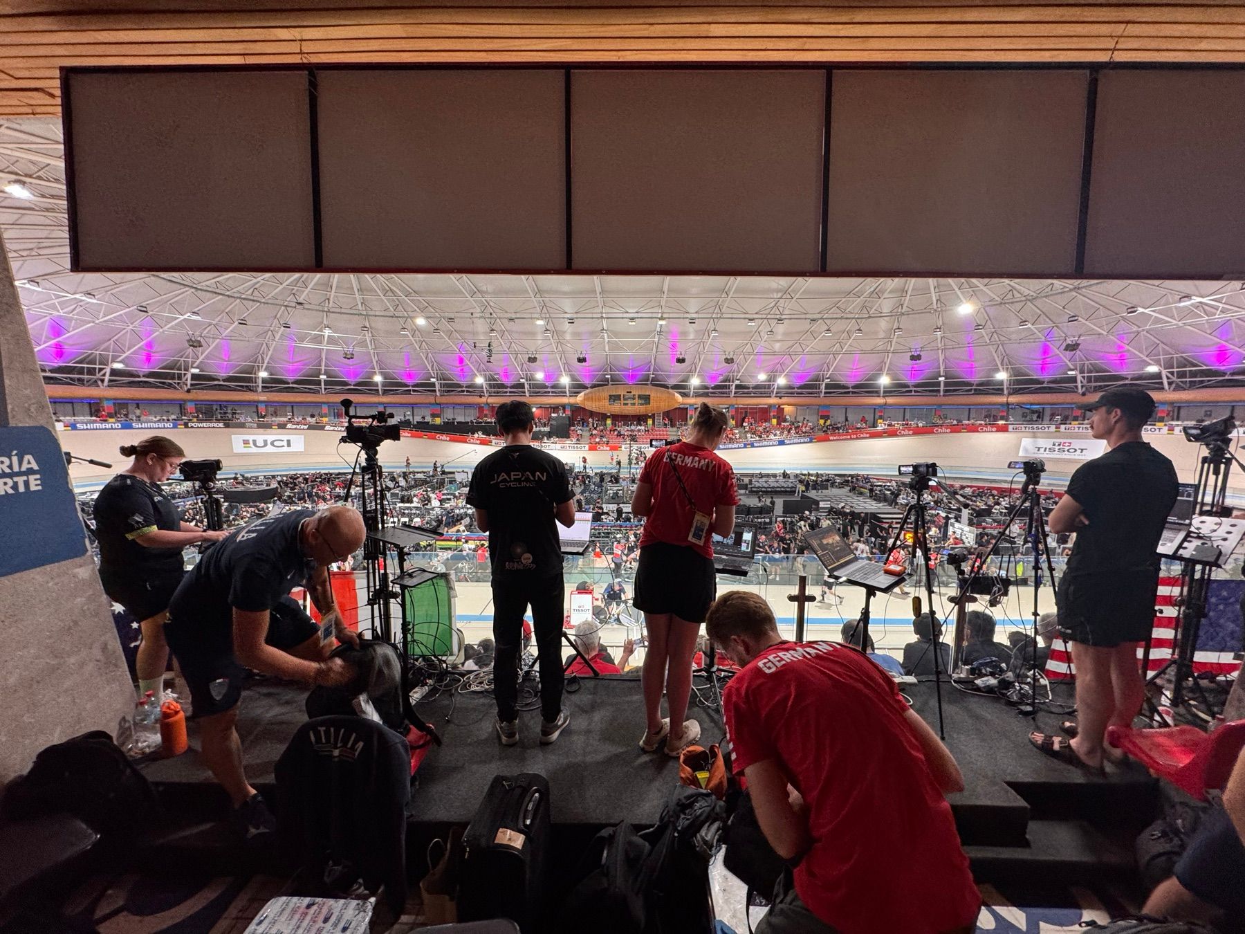Posiciones de prensa en el velódromo: operadores de cámara con trípodes y computadores conectados frente a la pista